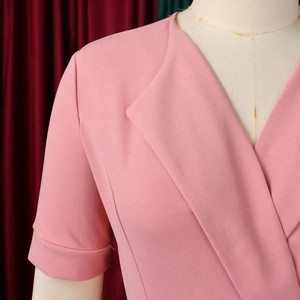 Detail of pink V-neck pleated dress featuring a wrap style and crepe textured fabric
