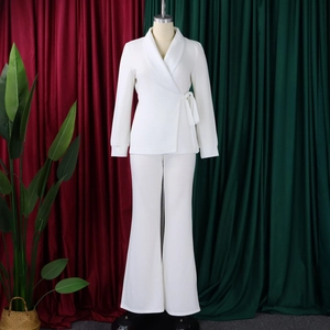 Detailweergave van wit tweedelig pak met wikkelblazer en pantalon met hoge tailleband