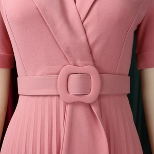 Detailed close-up of pink pleated dress waist featuring a matching fabric-covered belt