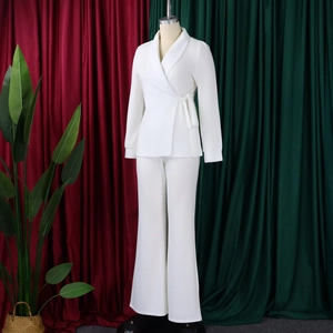 Detail van witte wikkelblazer met zijstrik en wijde broek op een paspop
