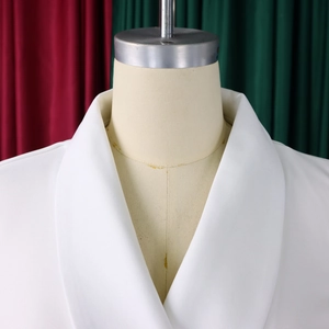 Detailweergave van een witte blazer met elegante sjaalkraag en hoogwaardige textuurstof