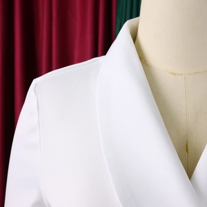 Detail van de revers en schouderpasvorm van een witte blazer op een etalagepop