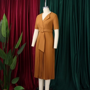 Close-up of elegant ginger yellow V-neck dress featuring pleated skirt and waist belt