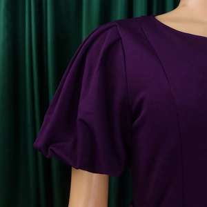 Detailed close-up of dark purple dress featuring elegant puff sleeves and knit fabric texture
