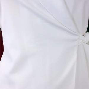 Detail van witte overslagblazer met tailleband en elegante V-hals reversstructuur