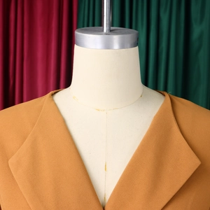 Detailed view of ginger yellow blazer with notched lapel and woven texture on a mannequin