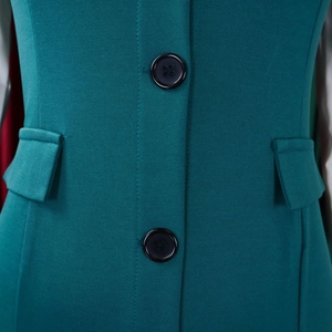 Detail view of teal business dress featuring black buttons and symmetrical pocket flaps