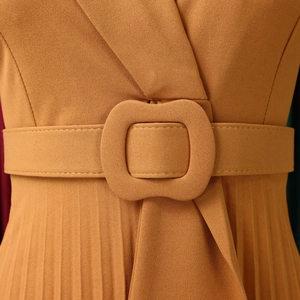 Detail of mustard yellow pleated dress showing wide waist belt and fabric buckle