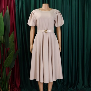 Detail of round neck beige A-line dress with puff sleeves and gold buckle belt