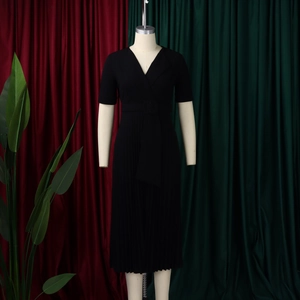 Detail of V-neck pleated black dress with belted waist and premium draped fabric