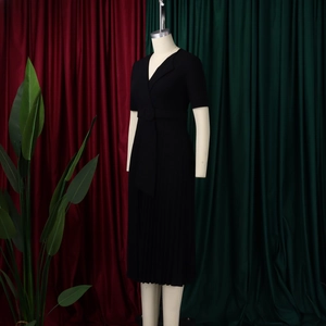 Detail of elegant V-neck short sleeve dress featuring a pleated skirt and matching belt