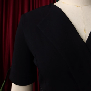 Detailed view of the elegant black V-neckline and pleated shoulder design on a dress
