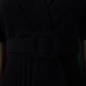 Detail of elegant black pleated dress showing waist belt with large decorative buckle