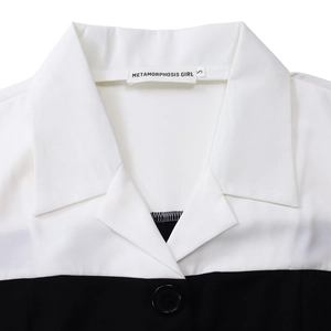Detail of a chic monochrome blazer dress featuring white lapels and black button closure