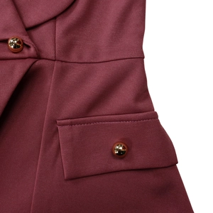 Detail of burgundy blazer featuring lapel collar, pocket flap and gold metal buttons
