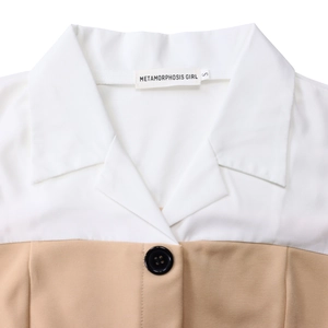 Detail of lapel collar with button and Metamorphosis Girl brand label on dress