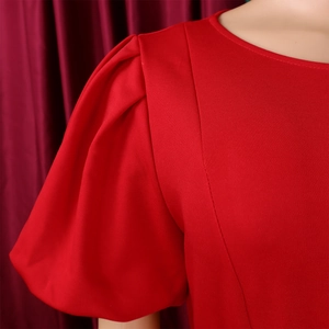 Detail of elegant red dress featuring pleated puff sleeves and smooth crew neckline texture