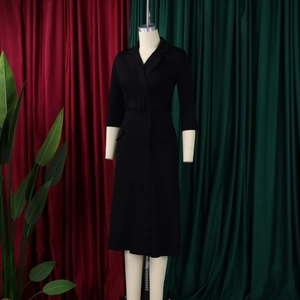 Detail van een zwarte blazer-midijurk met dubbele rij knopen en bijpassende ceintuur