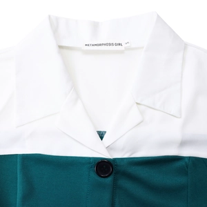 Detail of color-block notched lapel collar with black button on a green and white dress
