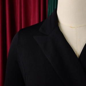 Detailopname van de gepiekte revers en schoudernaden van een zwarte blazerjurk
