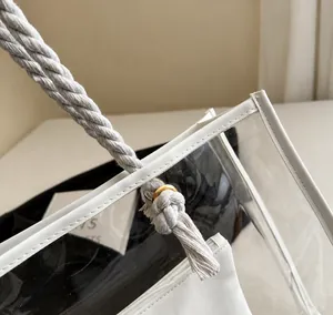 Detail der weißen Baumwollkordelgriffe und Goldringe an der transparenten PVC-Tragetasche