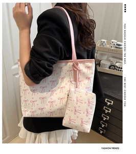 Detail of white bow print tote bag with pink straps and decorative knotted connectors