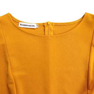 Detailed close-up of crew neckline and brand tag on mustard yellow A-line dress
