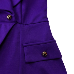 Detailaufnahme der violetten Stoffstruktur mit Falten und goldenem Metallknopf
