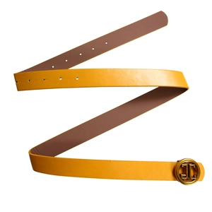 Detail view of ginger yellow leather belt with golden circular geometric buckle