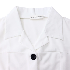 Close-up of a white lapel collar with a black contrast button and brand label