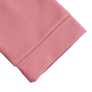 Detailed view of pink V-neck dress hemline with textured fabric and precise stitching