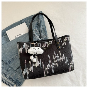 Detail of black canvas tote bag with heartwave embroidery and white cloud pendant