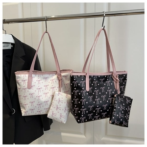 Detail view of tote bag set featuring pink bow prints in cream and black leather finishes