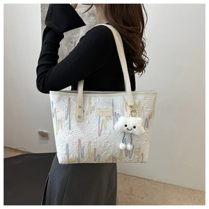 Close-up of embroidered white tote bag with brand logo and soft plush cloud charm
