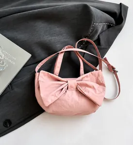 Detail shot of a pink bow shoulder bag featuring textured fabric and dual strap design