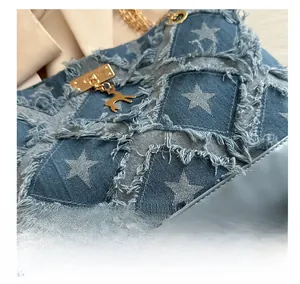 Detail of denim tote bag showing frayed fringe, star patterns, and gold deer pendant