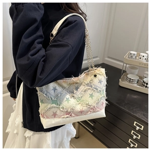 Detail of denim bucket bag showing rainbow star embroidery and fringe tassel edges