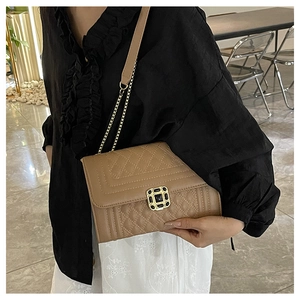 Close-up of camel quilted shoulder bag with gold square clasp and elegant chain strap