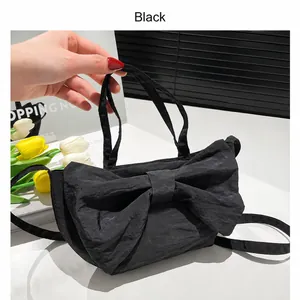 Close-up of black pleated nylon bag featuring a large bow and versatile strap