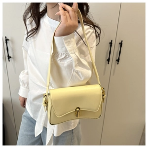Detail of a creamy yellow shoulder bag featuring a gold metal twist lock and leather strap