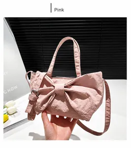 Detail of pink bow-shaped handbag with adjustable strap and ruffled texture design