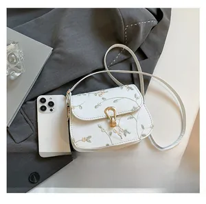 Mini sacoche en toile blanche avec broderies florales à côté d'un smartphone pour comparer la taille