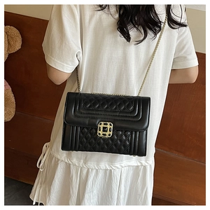 Close-up of the black quilted crossbody bag with a gold chain strap and metal lock