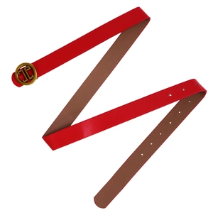 Detail of red leather belt with interlocking gold buckle and textured inner lining