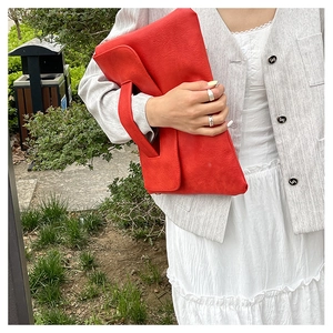 Details einer leuchtend roten übergroßen Clutch aus strukturiertem Leder mit breitem Griff