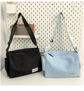 Detalle de correas negras ajustables y etiquetas blancas en bolsos negros y azul claro