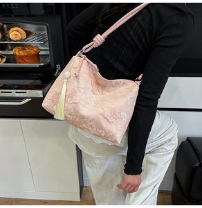 Dettaglio borsa in seta rosa con ricamo floreale e applicazioni di farfalle 3D
