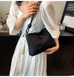 Detail of black silk bag featuring butterfly embroidery and tassel bead charm accessory