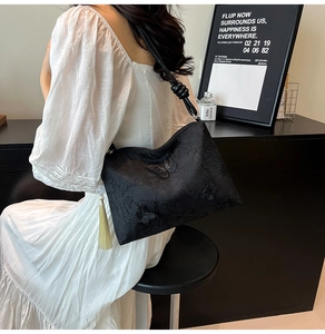 Dettaglio borsa a spalla in jacquard nero con ricamo farfalla 3D e nappa decorativa