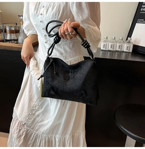 Detail of black jacquard shoulder bag with butterfly patterns and knotted handle tassel